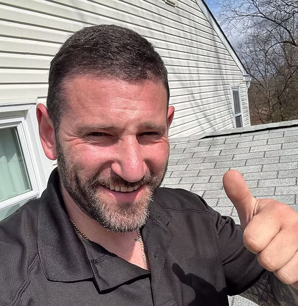 Alex Martinez giving a thumbs up outside a remodeled home roof