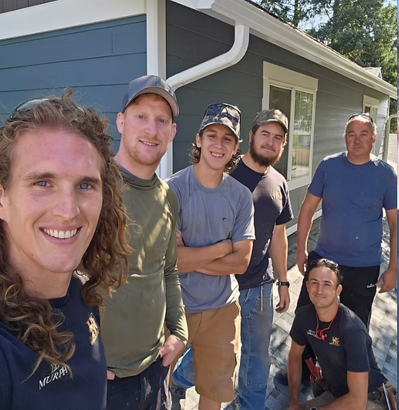 Jesee Delaverne with remodeling crew smiling outside a home